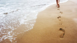 A young woman walking on the sand.